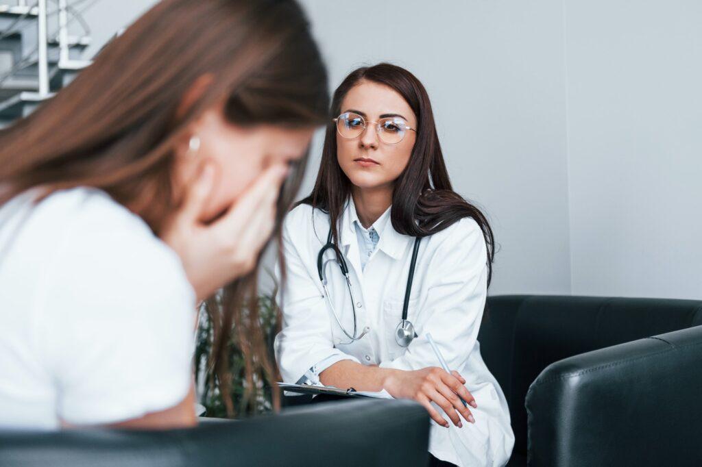 Girl have mental breakdown and crying. Young woman have a visit with female doctor in modern clinic