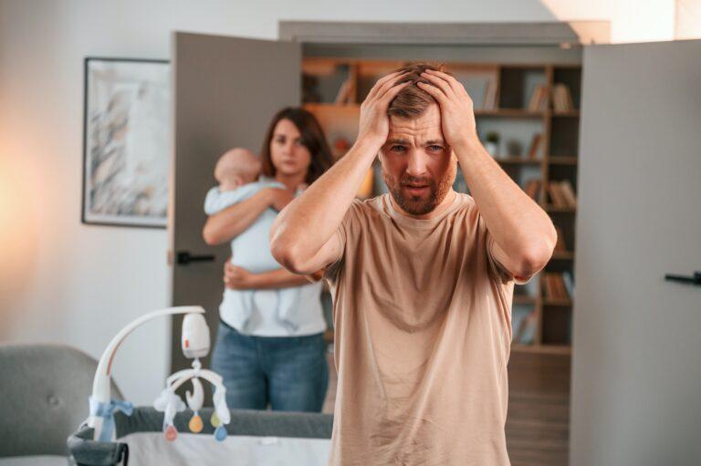 Having a headache. Conception of stress. Couple with newborn baby is at home having conflict